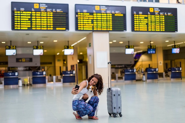 Frau mit Hund macht ein Selfie am Flughafen