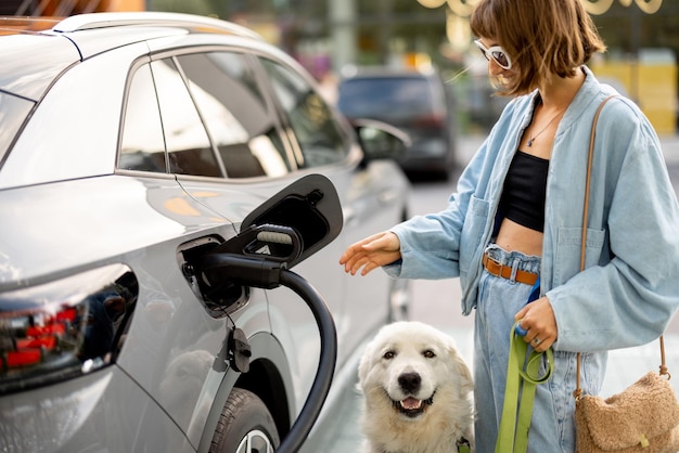 Foto frau mit hund zieht einen ladestecker aus ihrem elektroauto