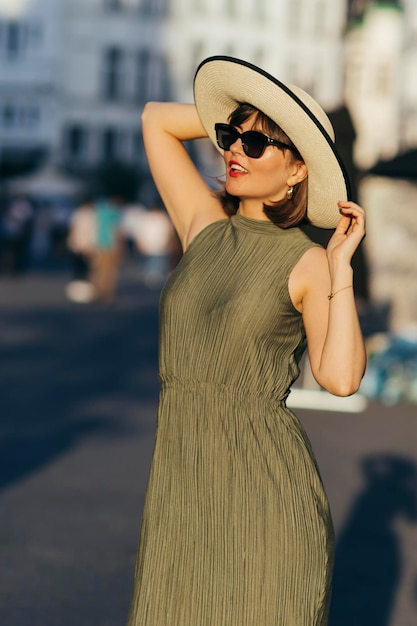 Frau mit Hut, die an einem sonnigen Tag in der Stadt spaziert