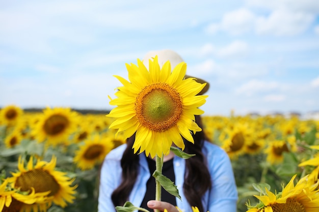 Frau mit Hut im Sonnenblumenfeld, die die Natur genießt