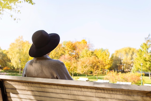 Frau mit Hut sitzt im Herbstpark