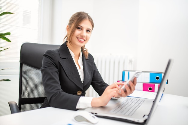 Frau mit ihrem Handy in ihrem Büro