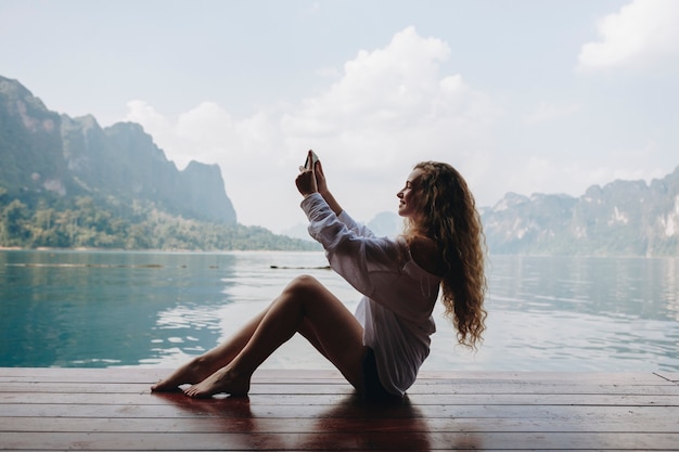 Frau mit ihrem Telefon an einem See