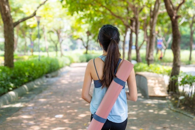 Frau mit ihrer Yogamatte im Park