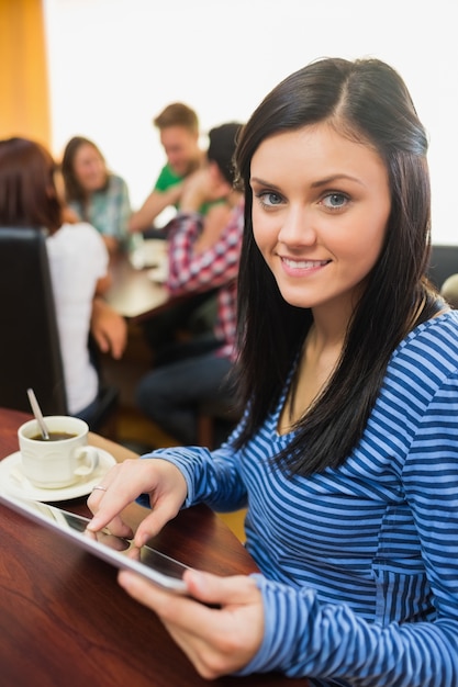 Frau mit Kaffee unter Verwendung des Tablet-PCs in der Kaffeestube