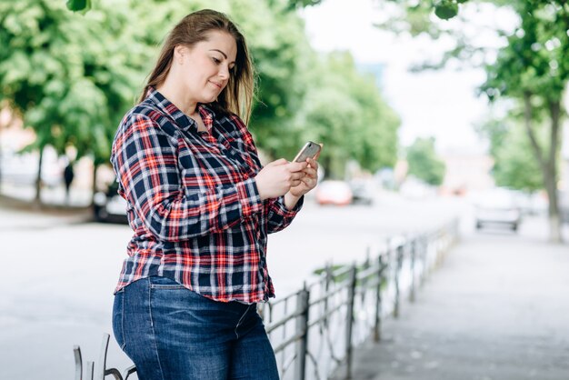 Frau mit kariertem Hemd im Park mit Handy