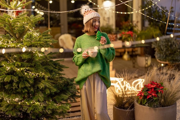 Frau mit Keks und Tasse an Silvester dekorierten Hinterhof