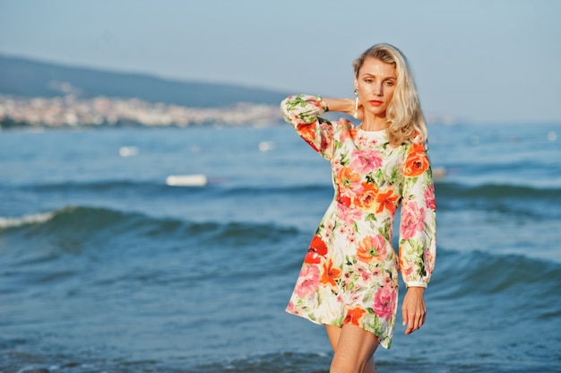 Frau mit Kleid steht am Sandstrand auf See