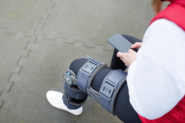 Frau mit Knieorthese oder Orthese nach einer Beinoperation im Park