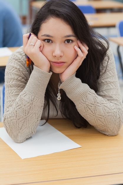 Frau mit Kopf in den Händen im Klassenzimmer