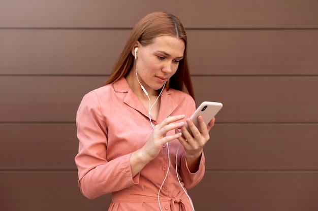 Frau mit Kopfhörern, während sie ihr Smartphone hält