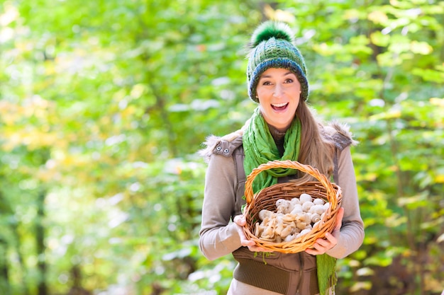 Frau mit Korb voll von Champignons im Wald