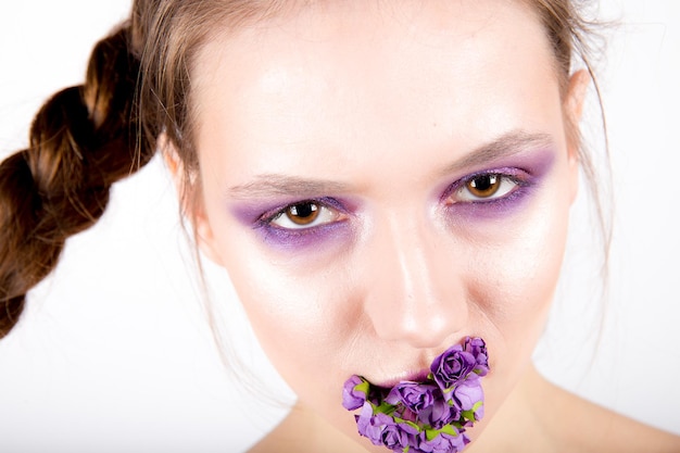 Foto frau mit kreativem make-up und blumen im mund