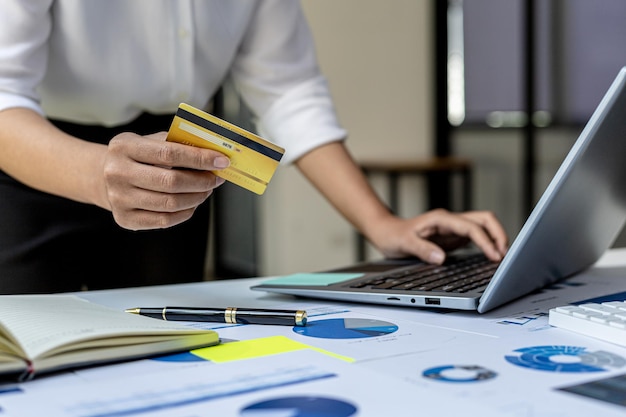 Frau mit Kreditkarte und Eingabe auf einer Laptop-Tastatur, sie füllt Kreditkarteninformationen aus, um eine Bestellung auf einer Internet-Shopping-Site zu bezahlen. Online-Shopping und Kreditkartenzahlungskonzept
