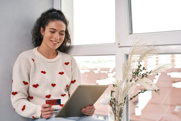 Frau mit Kreditkarte und Tablet beim Online-Shopping im Internet