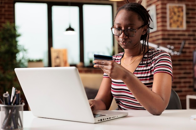 Frau mit Kreditkarte, Zahlung im Online-Shop, elektronisches Einkaufen, E-Commerce-Konzept. Junge Person mit Brille kauft Produkte mit Laptop, Käufer bezahlt für Bestellung