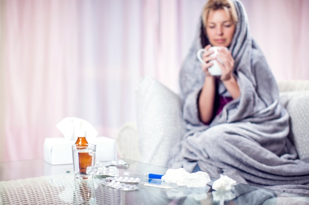 Frau mit kurzen blonden Haaren bekam die Grippe und trank zu Hause heißen Tee. Konzept für Menschen, Gesundheitswesen und Medizin