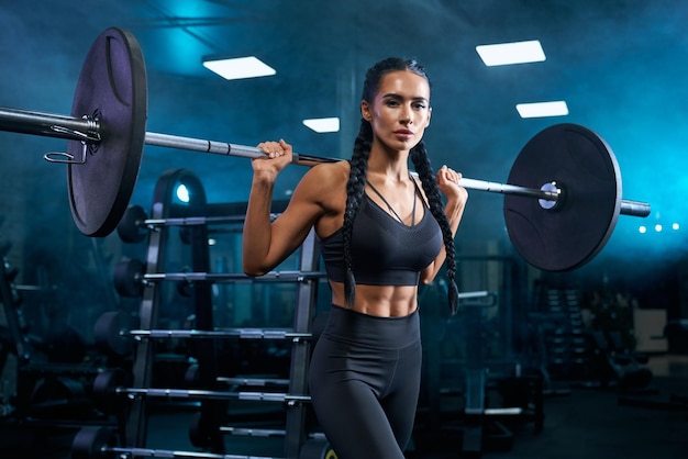 Frau mit Langhantel auf den Schultern im Fitnessstudio