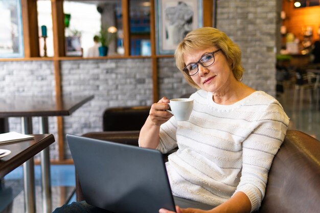 Frau mit Laptop arbeitet in einem Café im Büro, sie ist Freiberuflerin.