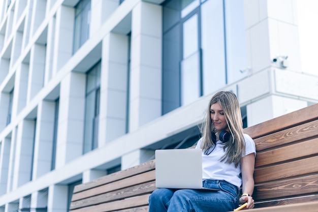 Frau mit Laptop auf Bank außerhalb