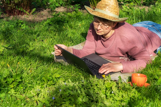 Frau mit Laptop auf Frühlingswiese Die Idee einer effektiven Unternehmensführung in der Natur