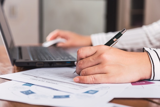 Frau mit Laptop-Computer, der mit Stift arbeitet und schreibt.