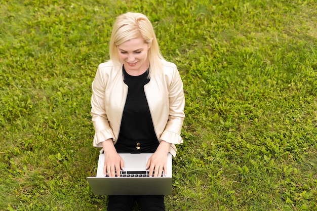 Frau mit Laptop entspannt im Park.