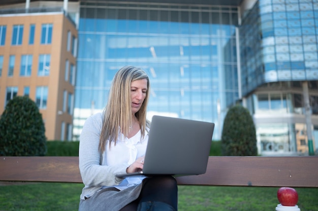 Frau mit Laptop im Garten einer Bürofläche