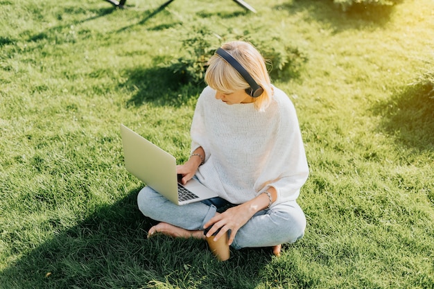 Frau mit Laptop sitzt auf dem Gras
