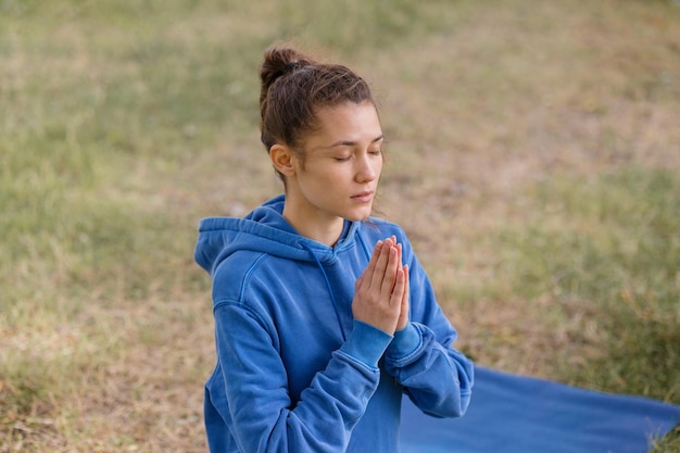 Frau mit lockigem Haar meditiert in einem Park Yoga und Meditation für geistige und körperliche Gesundheit