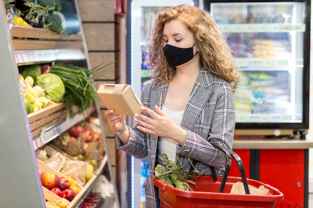 Frau mit Maske, die Lebensmittel kauft