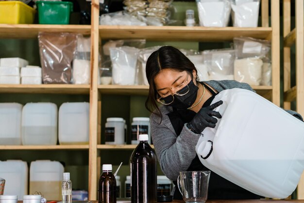 Frau mit Maske in einem Lagerhaus, das chemische Produkte verarbeitet.