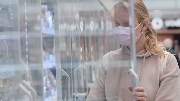 Frau mit Maske kauft Joghurt im Supermarkt