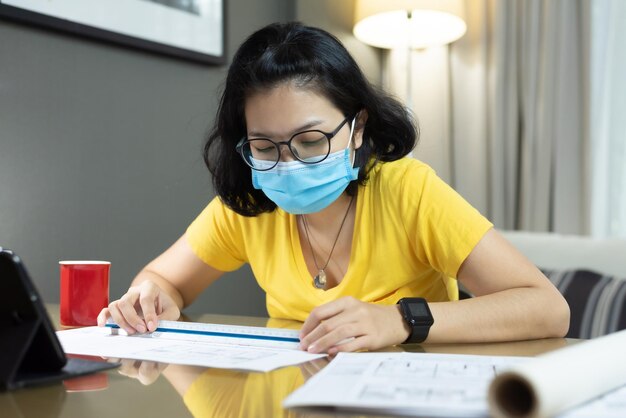 Frau mit Maske misst Papier auf dem Tisch