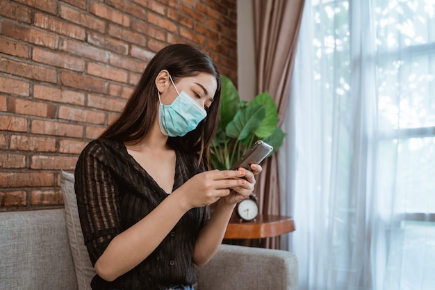 Frau mit Masken, die Handy für soziale Distanzierung verwenden