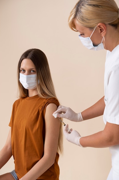 Foto frau mit medizinischer maske, die einen impfstoff erhält