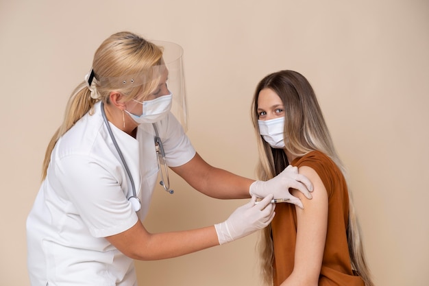 Frau mit medizinischer Maske, die einen Impfstoff erhält
