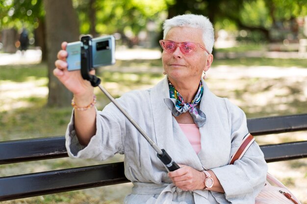 Frau mit mittlerer Aufnahme, die ein Selfie auf der Bank macht