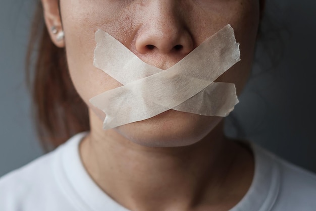 Frau mit Mund in Klebeband versiegelt. Redefreiheit, Pressefreiheit, Menschenrechte, Protestdiktatur, Demokratie, Freiheit, Gleichheit und Brüderlichkeitskonzepte