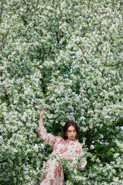 Frau mit natürlichem Make-up, Blumenkosmetik für die Gesichtshaut, Mädchen posiert in Blumenzweigen des blühenden Apfelbaums im Frühjahr