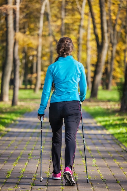 Frau mit nordischen Wanderstöcken auf Park