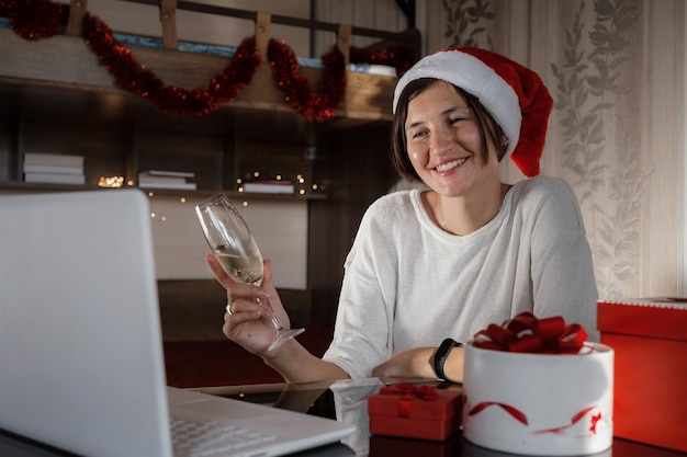 Frau mit Notebook-Computer zu Hause in Weihnachtsmütze Winterferienverkäufe