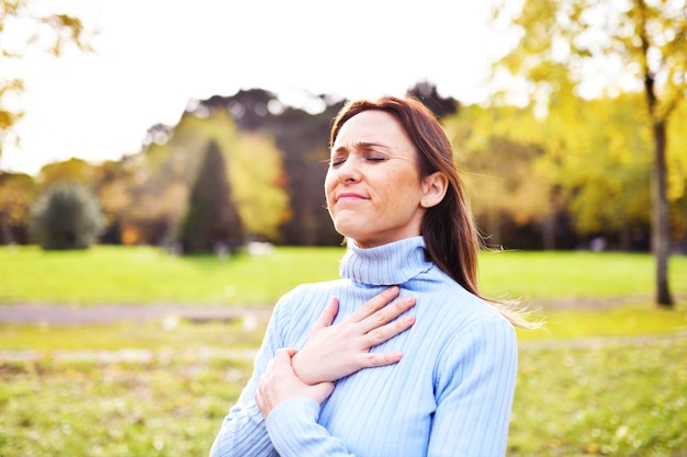 Frau mit offenen Armen, die im Herbst oder Winter frische, saubere Luft im Busch oder Feld atmet