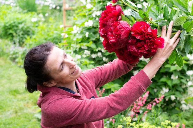 Frau mit Pfingstrosen im Garten