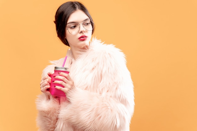 Frau mit rosafarbenem trinkendem Glas auf Gelb