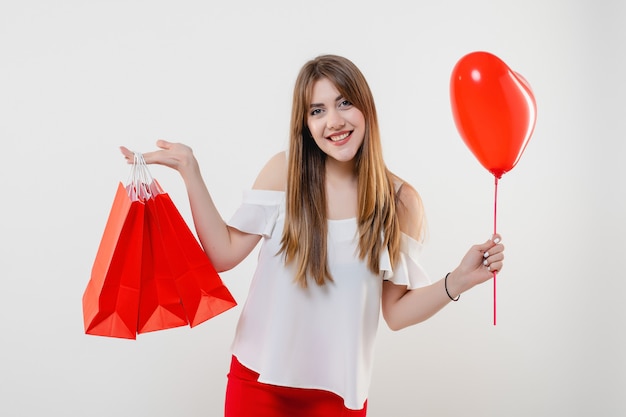 Frau mit rotem Herzen formte den lokalisierten Ballon und Einkaufstaschen