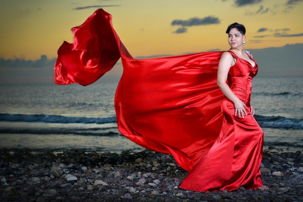 Foto frau mit rotem regenschirm steht am strand