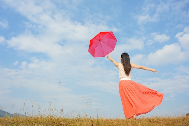 Frau mit rotem Regenschirm und blauem Himmel