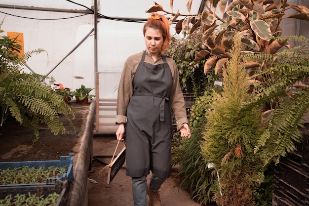 Frau mit roten Haaren, die in einem großen professionellen Gewächshaus arbeitet