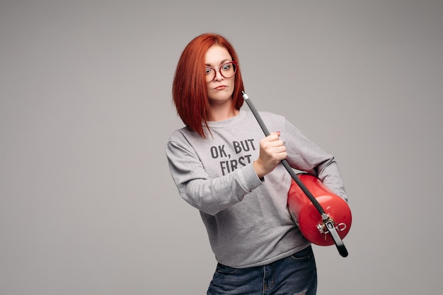 Frau mit roten Haaren in der Hand eines Feuerlöschers